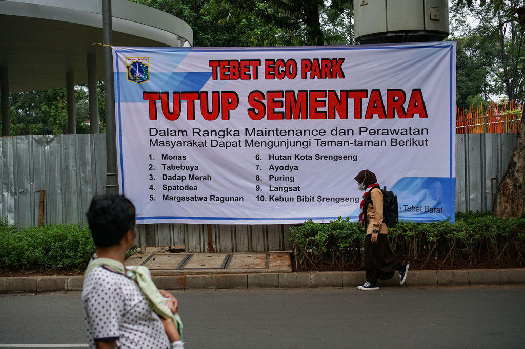 Warga berjalan di dekat spanduk informasi penutupan sementara Tebet Eco Park di Tebet, Jakarta, Rabu, 15 Juni 2022.