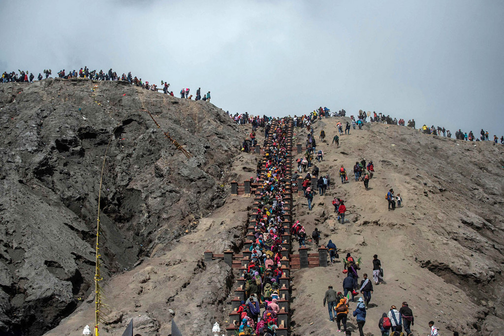 Warga Suku Tengger membawa sesaji untuk dilarung di kawah Gunung Bromo.