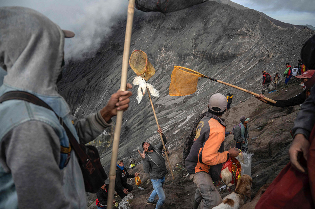 Warga berebut sesaji yang dilempar oleh masyarakat Suku Tengger ke kawah Gunung Bromo pada Upacara Yadnya Kasada di Desa Ngadisari, Sukapura, Probolinggo.