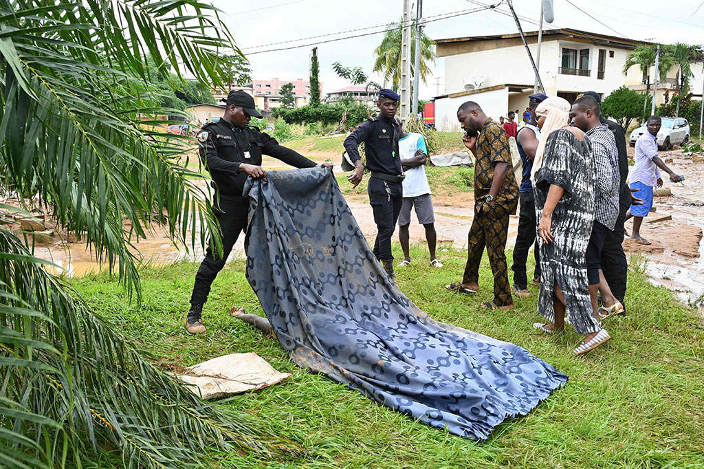 Seorang polisi menutupi jenazah seorang pria di daerah pemukiman yang terendam banjir di Bingerville, dekat Abidjan, Pantai Gading pada Selasa, 21 Juni 2022.