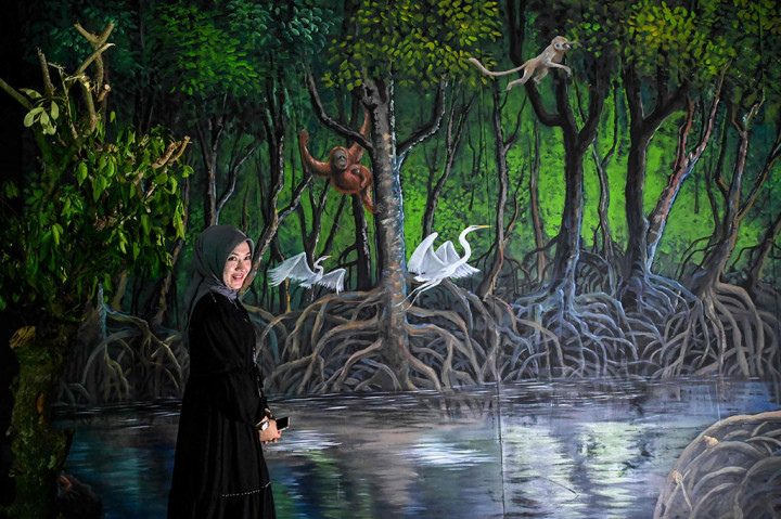 Pengunjung berfoto dengan latar belakang lukisan binatang dalam kawasan hutan pesisir dan perkampungan rumah nelayan pada pameran tematik bertajuk The Animal Instinct di Museum Tsunami Aceh, Banda Aceh, Kamis, 23 Juni 2022. 