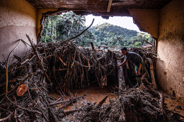 Warga mencari barang-barang miliknya yang tersisa di puing-puing rumah yang rusak akibat diterjang banjir bandang di Desa Purasari, Leuwiliang, Bogor, Jumat, 24 Juni 2022. 