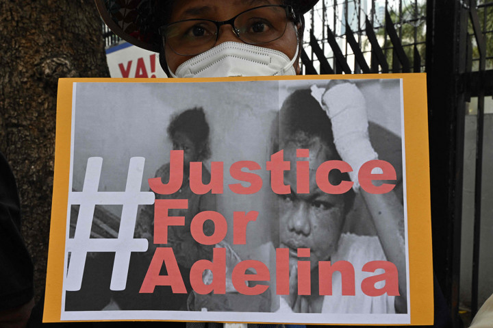 Massa tampak membawa poster bertulisan '#justiceforAdelina'.