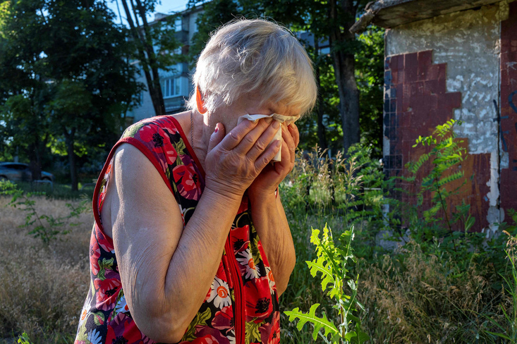 Seorang wanita menangis ketika penyelamat mengevakuasi tubuh suaminya yang tewas dalam serangan roket di daerah perumahan di Kharkiv pada 27 Juni 2022. 
