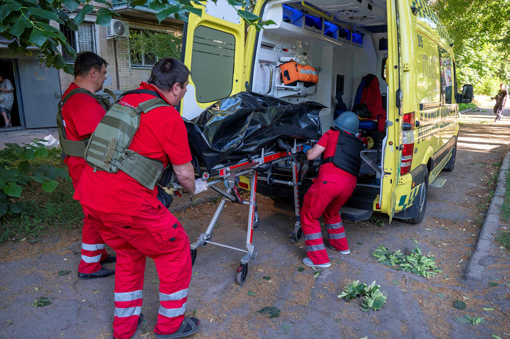 Tim penyelamat tampak mengevakuasi para korban luka dan membawa mereka dengan tandu ke ambulans-ambulans.