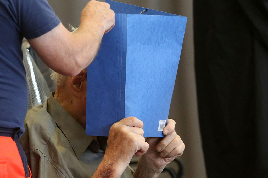 Mantan penjaga kamp konsentrasi Nazi Josef Schuetz (kedua dari kanan) menutupi wajahnya saat akan menjalani sidang vonis di sebuah gym yang digunakan sebagai ruang sidang darurat di Brandenburg an der Havel, Jerman timur, Selasa, 28 Juni 2022.