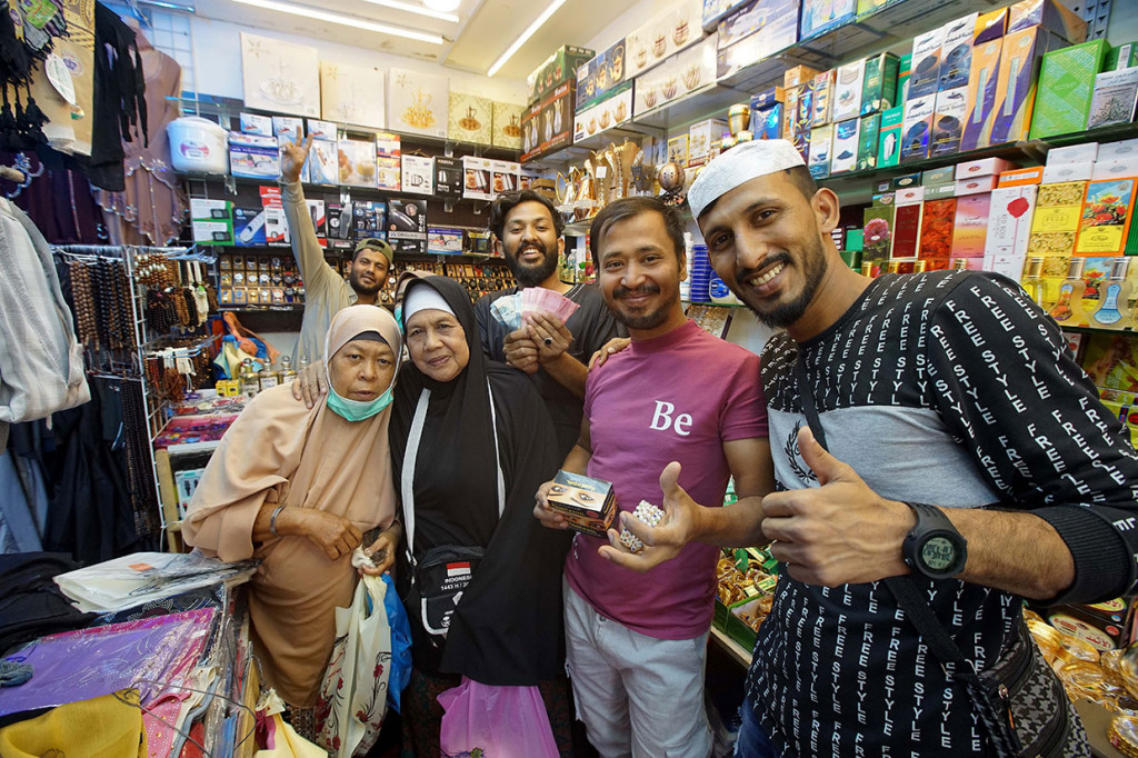 Jemaah haji Indonesia berfoto bersama penjual saat berbelanja di toko peralatan ibadah dan suvenir di kawasan Mekkah, Arab Saudi, Jumat, 1 Juli 2022.