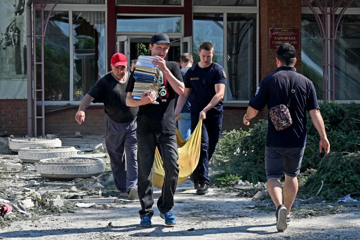 Petugas tanggap darurat dan sukarelawan Ukraina membereskan berbagai barang yang penting dari dampak serangan rudal di sekolah dasar di Kharkiv.