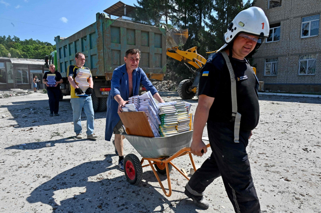Para pegawai sekolah dibantu petugas penyelamat mengeluarkan buku-buku dan sejumlah barang dari dalam sekolah yang hancur dihantam rudal Rusia, di Distrik Shevchenkivskiy Kharkiv, Ukraina.