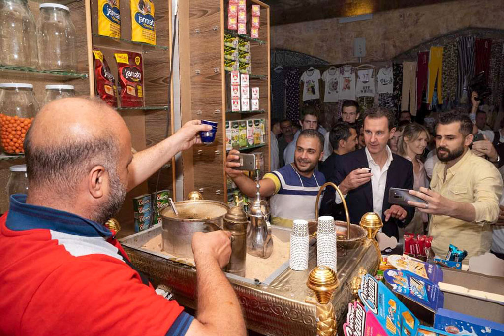 Presiden Suriah Bashar al-Assad (kedua-kanan) minum kopi di pasar bersejarah Aleppo, Jumat, 8 Juli 2022.