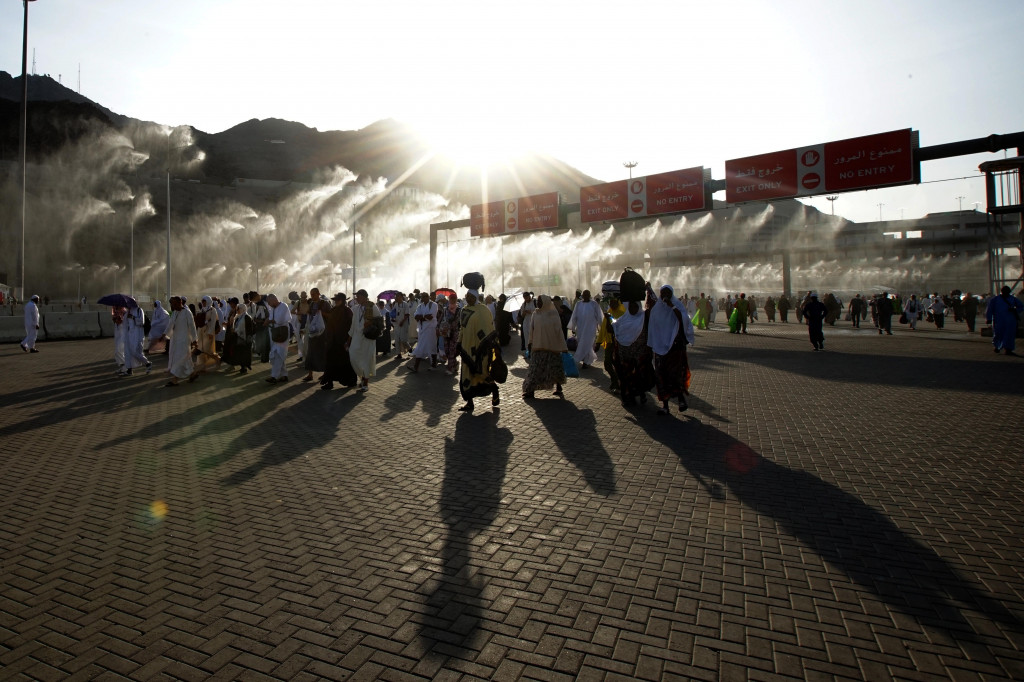 Jemaah haji berjalan melalui gerbang penyemprot air usai melakukan lempar Jumrah di Jamarat, Mina, Mekkah, Arab Saudi, Senin, 11 Juli 2022.