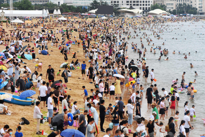 Ratusan warga memadati pantai di Qingdao, Shandong, Tiongkok, Minggu, 10 Juli. Pemerintah Tiongkok mengeluarkan peringatan gelombang panas, Rabu, 13 Juli 2022, seusai sejumlah provinsi dan puluhan kota mengalami kenaikan suhu panas hingga mencapai 40 derajat celsius.