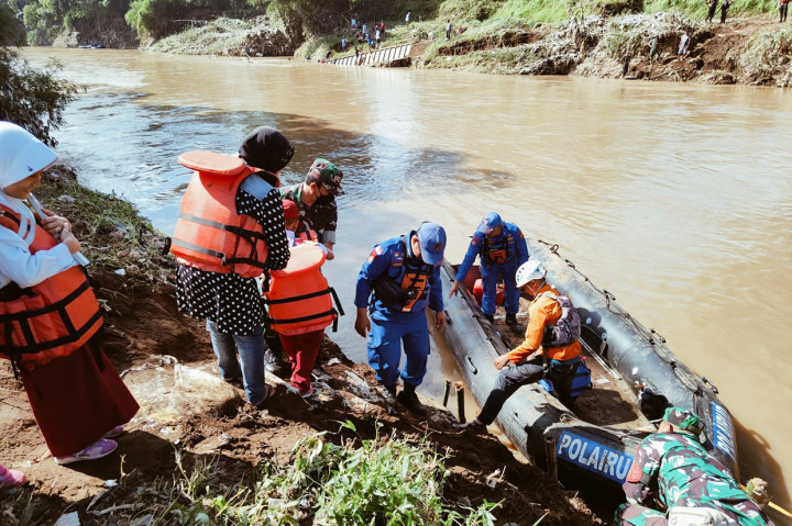Puluhan siswa dan orangtua dari Kampung Pananggungan, Kecamatan Karangpawitan, Garut, Jawa Barat menaiki perahu karet untuk berangkat ke sekolah di hari pertama masuk sekolah Senin, 18 Juli 2022, pagi, setelah dua jembatan putus diterjang banjir bandang.