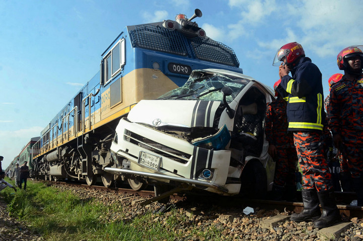 Personel pemadam kebakaran berdiri di samping puing-puing kendaraan minibus setelah ditabrak kereta api di Mirershorai dekat Chattogram, Bangladesh, Jumat, 29 Juli 2022.