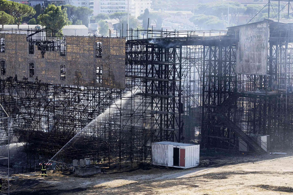 Petugas pemadam kebakaran melakukan pembasahan di sebuah bangunan untuk memadamkan api di studio Cinecitta di sebelah tenggara Roma, pada Senin, 1 Agustus 2022.
