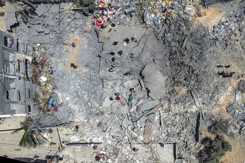 Pemandangan udara menunjukkan warga Palestina memeriksa reruntuhan bangunan yang runtuh akibat serangan udara Israel di Kota Gaza, pada Sabtu, 6 Agustus 2022.