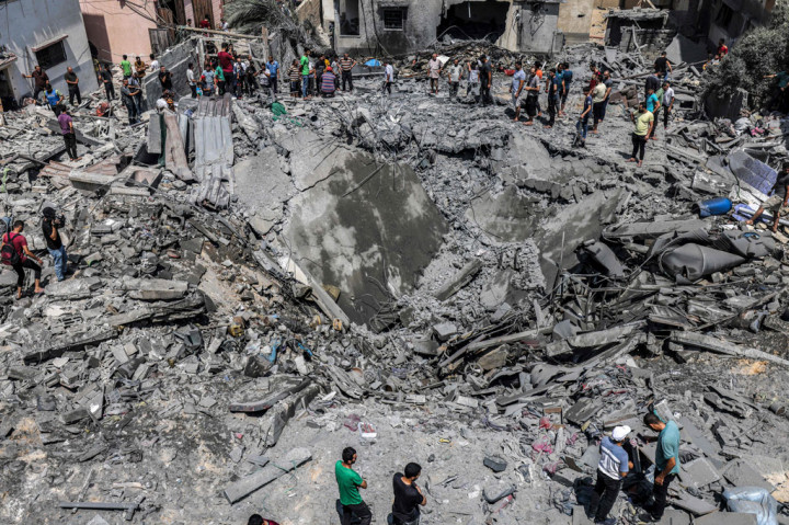 Pemandangan udara menunjukkan warga Palestina memeriksa reruntuhan bangunan yang runtuh akibat serangan udara Israel di Kota Gaza, pada Sabtu, 6 Agustus 2022.