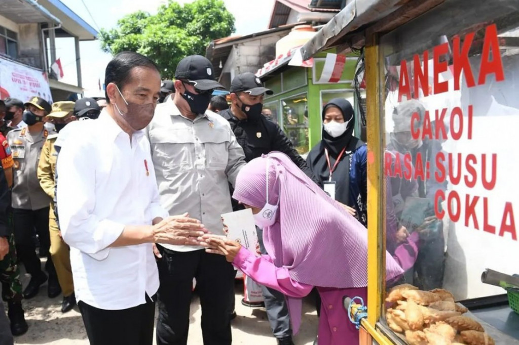 Presiden Joko Widodo didampingi Ibu Iriana Joko Widodo menyerahkan Bantuan Modal Kerja (BMK) dan Bantuan Langsung Tunai (BLT) minyak goreng kepada peserta Program Keluarga Harapan (PKH) di Pasar Sungai Duri, Kabupaten Bengkayang, Provinsi Kalimantan Barat, pada Selasa, 9 Agustus 2022.