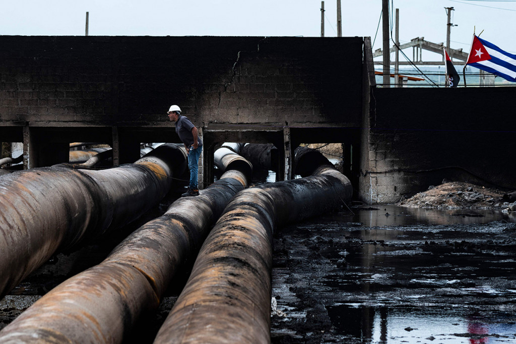 Besi dan material keras terlihat melengkung terbakar api. Selama berhari-hari kebakaran itu menimbulkan asap tebal hitam yang membubung tinggi ke udara.