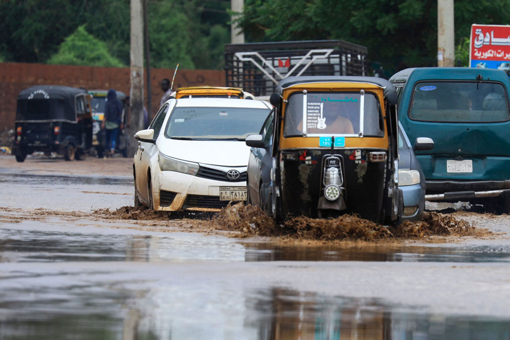 Kendaraan melaju di sepanjang jalan yang digenangi banjir menyusul hujan lebat di ibu kota Sudan, Khartoum, pada 13 Agustus 2022.