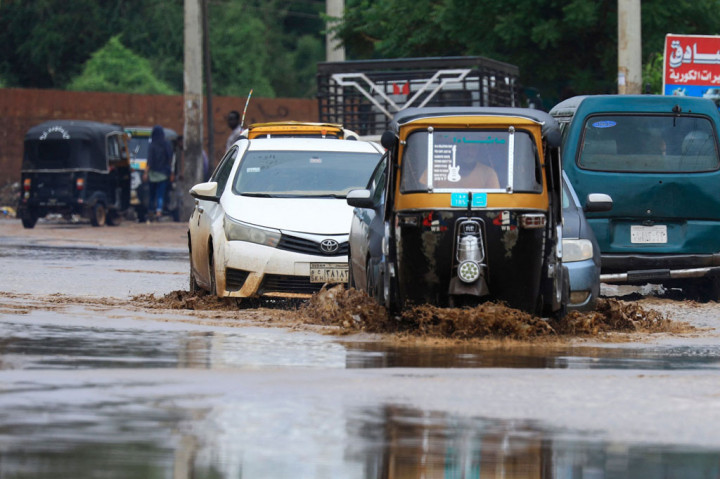 Kendaraan melaju di sepanjang jalan yang digenangi banjir menyusul hujan lebat di ibu kota Sudan, Khartoum, pada 13 Agustus 2022.