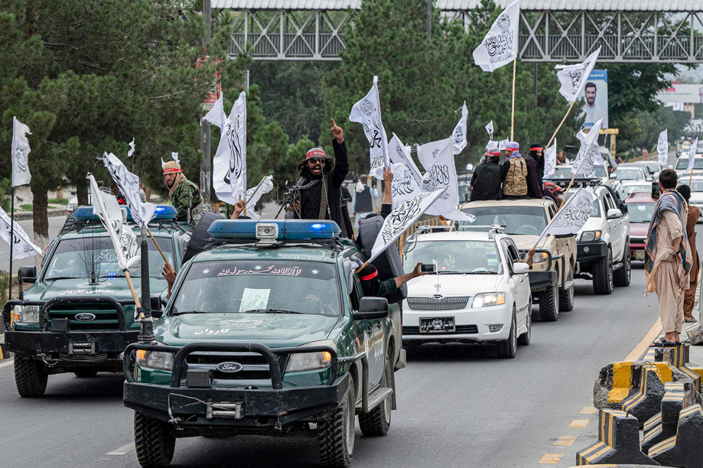 Pendukung Taliban berkonvoi menggunakan mobil sambil membawa bendera Imarah Islam Afghanistan.