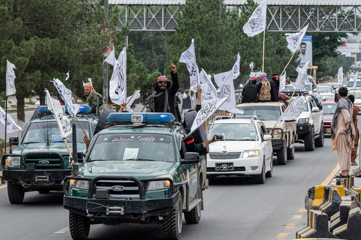 Pendukung Taliban berkonvoi menggunakan mobil sambil membawa bendera Imarah Islam Afghanistan.