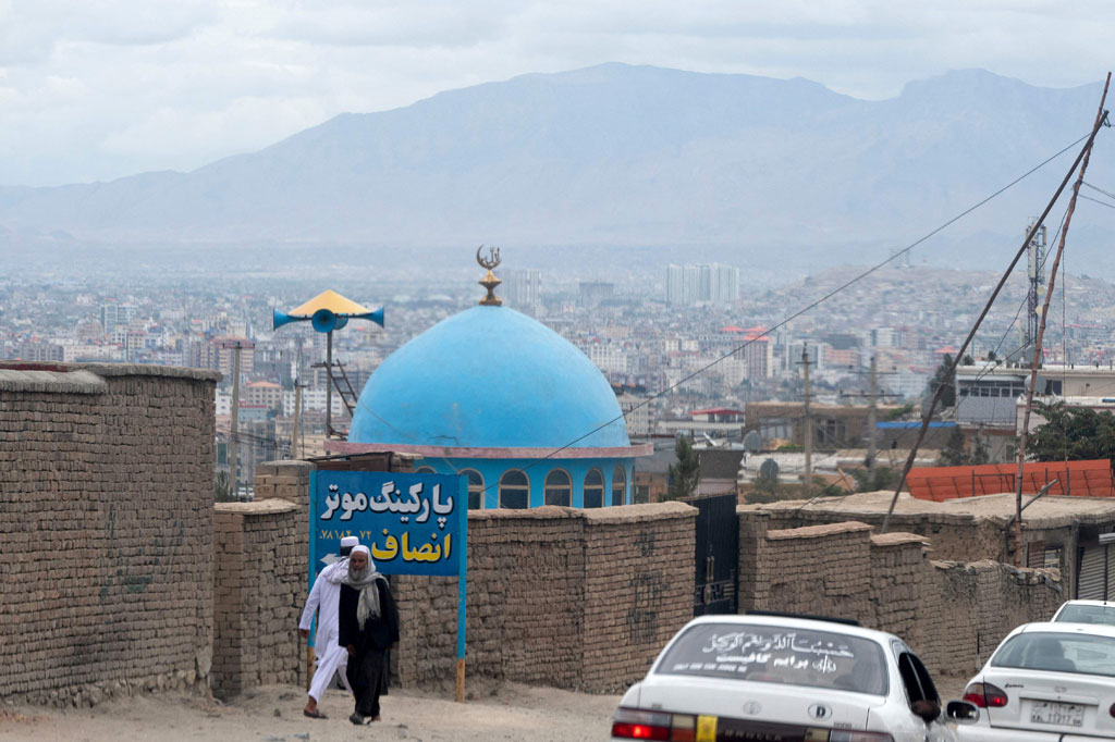 Pria Afghanistan berjalan melewati kubah biru sebuah masjid sehari setelah ledakan di pinggiran Kabul, Kamis, 18 Agustus 2022.