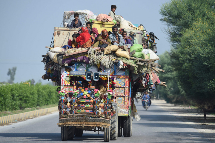 Korban banjir meninggalkan tempat tinggal mereka dan mengungsi ke tempat yang lebih aman menggunakan mobil truk.