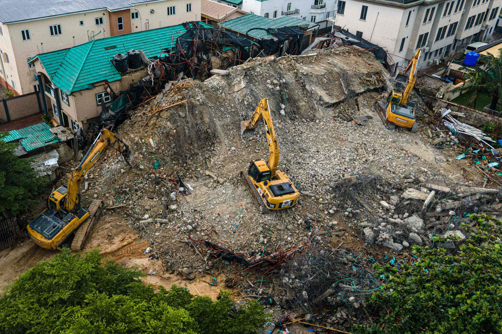 Petugas dibantu alat berat bekerja di lokasi runtuhnya bangunan tujuh lantai di Lekki, Lagos, Nigeria, Senin, 5 September 2022.