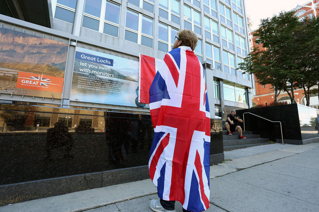 Seorang pria berkabung dalam bendera Union Jack berdiri di depan Komisi Tinggi Inggris setelah kematian Ratu Inggris Elizabeth II di Ottawa, Kanada, Kamis, 8 September 2022. 