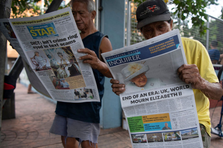 Orang-orang membaca surat kabar dengan halaman depan yang memberitakan meninggalnya Inggris Elizabeth II, di Manila, Filipina pada Sabtu, 10 September 2022.