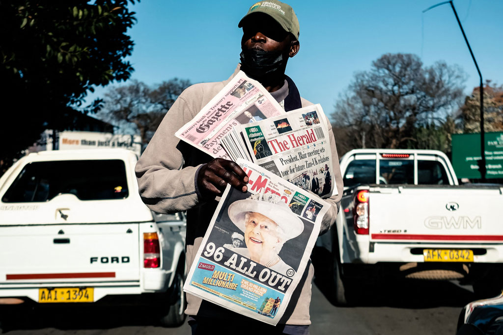 Seorang penjual surat kabar membawa kertas yang mengumumkan kematian Ratu Elizabeth II dengan judul 