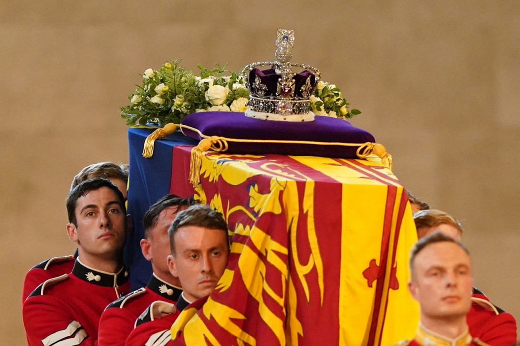 Peti Ratu yang dibungkus dengan bendera Royal Standard of Scotland dengan Mahkota kerajaan Imperial State Crown serta simbol kerajaan lainnya seperti orb dan spectre ditempatkan di atas bantal di samping karangan bunga, dibawa dalam prosesi yang penuh haru.