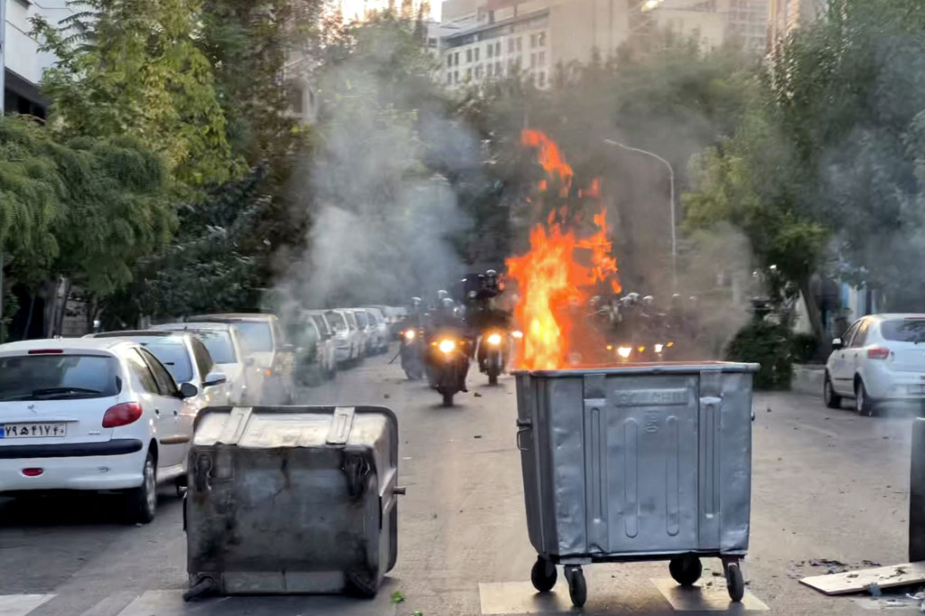 Tempat sampah yang terbakar di tengah persimpangan selama protes atas kematian Mahsa Amini, setelah ditangkap oleh polisi moral republik Islam itu, di Teheran pada Selasa, 20 September 2022.