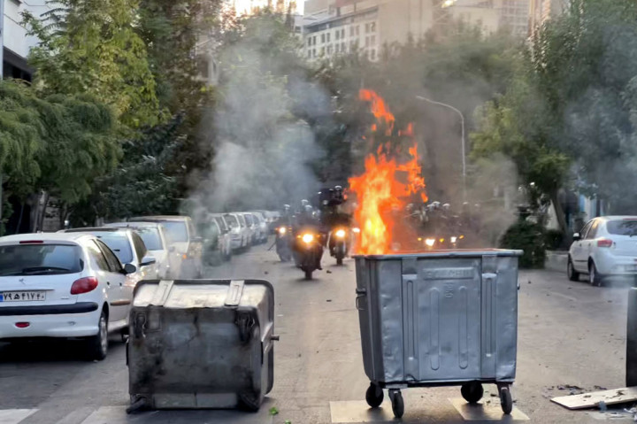Tempat sampah yang terbakar di tengah persimpangan selama protes atas kematian Mahsa Amini, setelah ditangkap oleh polisi moral republik Islam itu, di Teheran pada Selasa, 20 September 2022.