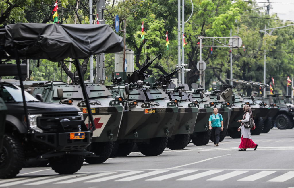 Pedagang melewati depan kendaraan tempur milik TNI yang dipamerkan di depan Kompleks Istana Kepresidenan, Jalan Medan Merdeka Utara, Jakarta Pusat, Selasa, 4 Oktober 2022.
