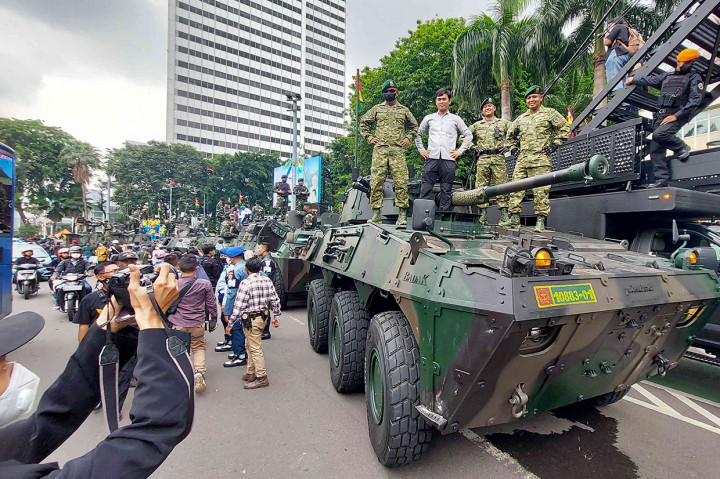 Warga berfoto bersama kendaraan tempur saat pawai alutsista usai upacara peringatan HUT ke-77 TNI, Jakarta, Rabu, 5 Oktober 2022.