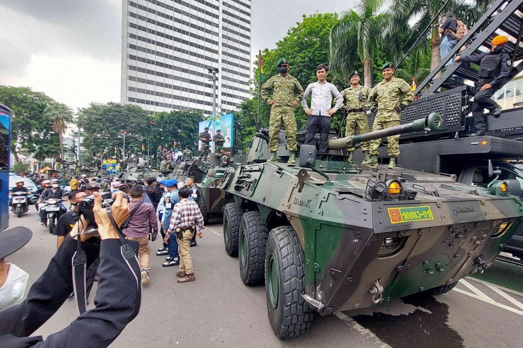 Warga menyaksikan iringan kendaraan tempur saat pawai alutsista usai upacara peringatan HUT ke-77 TNI, Jakarta, Rabu, 5 Oktober 2022.