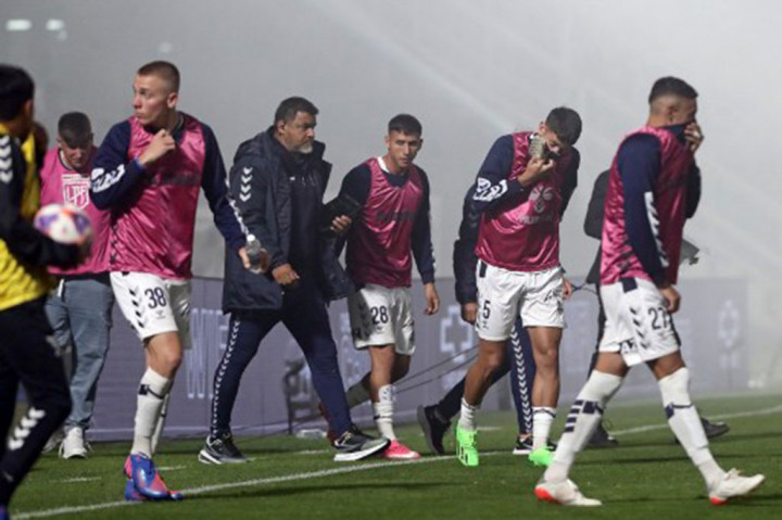 Para pemain Gimnasia y Esgrima berlarian menyelamatkan diri setelah gas air mata yang ditembakkan polisi memasuki stadion Juan Carmelo Zerillo selama pertandingan Turnamen Liga Sepak Bola Profesional Argentina 2022 antara Gimnasia y Egrima melawan Boca Juniors di La Plata, Argentina pada Kamis, 6 Oktober 2022 waktu setempat. 