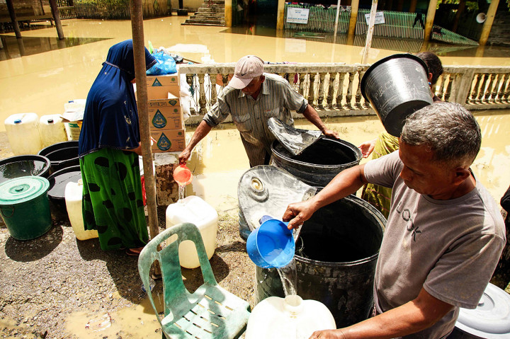 Warga mengumpulkan air bersih dari posko setelah rumahnya terendam banjir di Lhokseumawe, Aceh, pada 10 Oktober 2022.