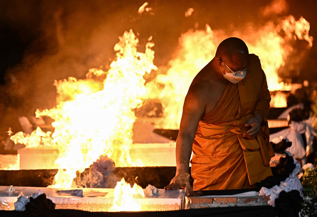 Para biksu membacakan doa untuk memulai seremoni itu, dengan warga setempat yang berduka turut hadir dan mengucapkan perpisahan dengan mereka yang tewas.
