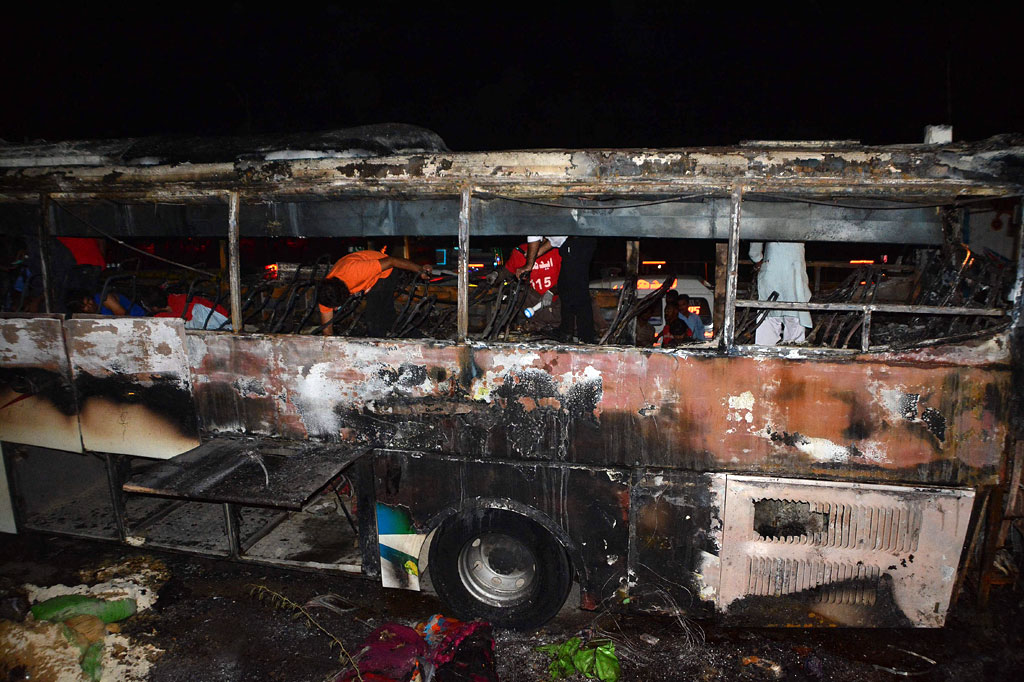 Relawan Edhi, sebuah yayasan nirlaba kesejahteraan sosial, mencari sisa-sisa penumpang bus yang terbakar setelah insiden kebakaran semalam di dekat Nooriabad, di Distrik Jamshoro Sindh, Pakistan, Kamis, 13 Oktober 2022 dini hari waktu setempat.