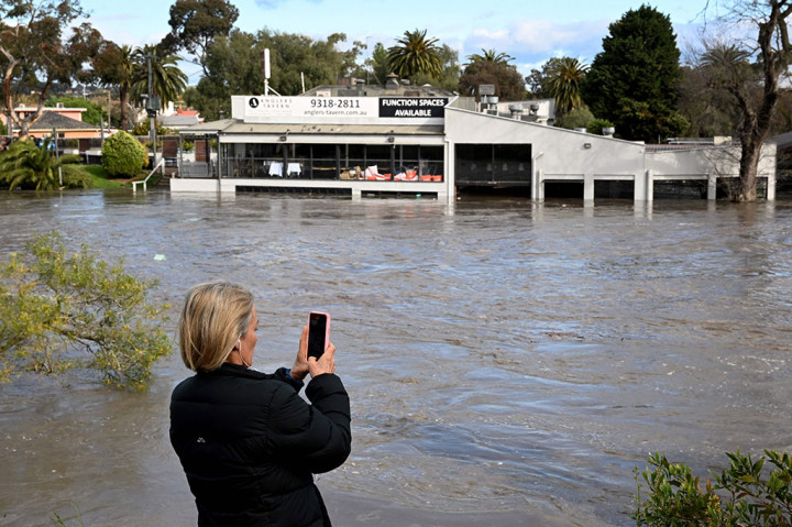 Seorang wanita merekam area banjir di pinggiran Maribyrnong, Melbourne.
