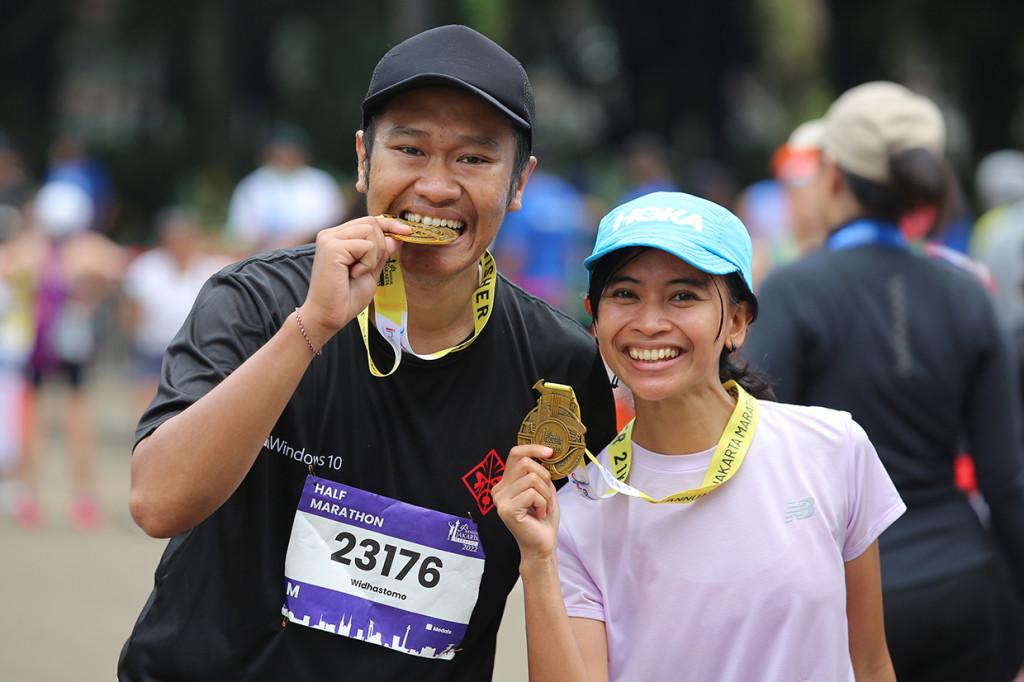 Peserta berfoto dengan memegang medali seusai mengikuti lari Jakarta Marathon 2022, Jakarta, Minggu, 16 Oktober 2022.