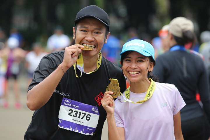 Peserta berfoto dengan memegang medali seusai mengikuti lari Jakarta Marathon 2022, Jakarta, Minggu, 16 Oktober 2022.