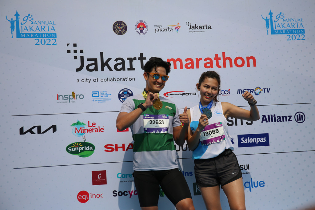 Peserta berfoto dengan memegang medali seusai mengikuti lari Jakarta Marathon 2022, Jakarta, Minggu, 16 Oktober 2022.