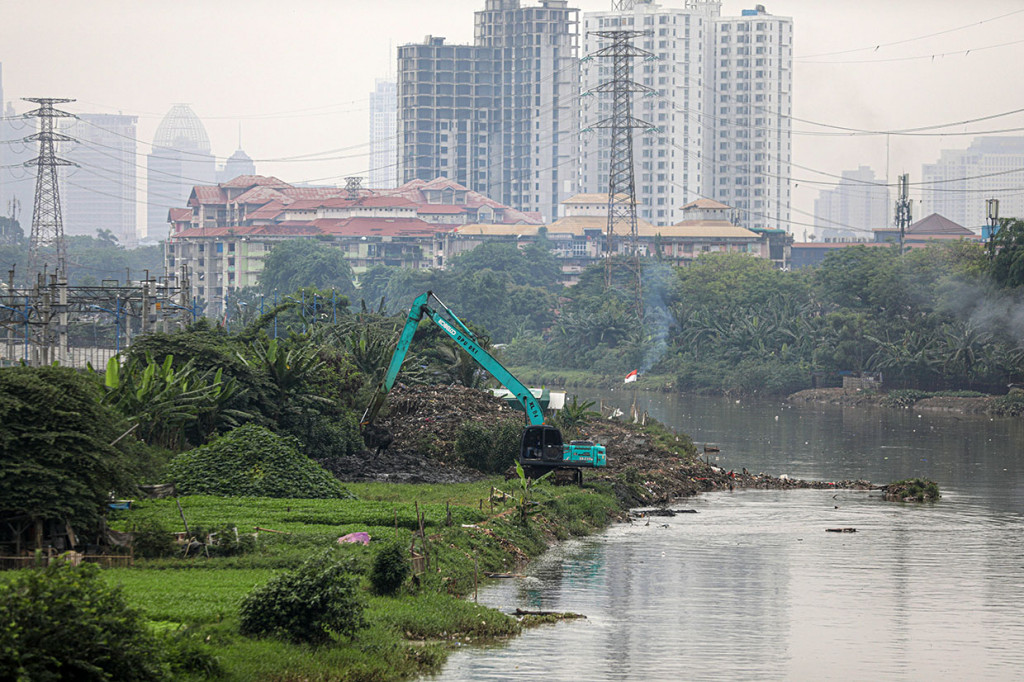 Petugas menggunakan eskavator melakukan pengerukan lumpur aliran sungai Kanal Banjir Barat di kawasan Petamburan, Jakarta, Rabu, 19 Oktober 2022. 