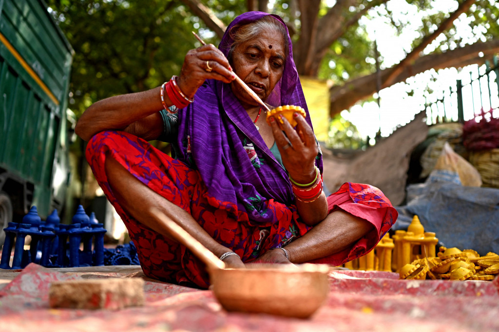 Seorang pembuat tembikar melukis lampu tanah jelang Festival Diwali di sepanjang pinggir jalan di New Delhi, India, 18 Oktober 2022.