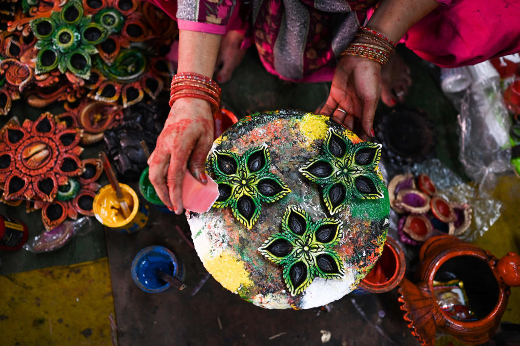 Seorang pembuat tembikar menuangkan lilin ke lampu tanah jelang Festival Diwali di sepanjang pinggir jalan di New Delhi, India, 18 Oktober 2022.